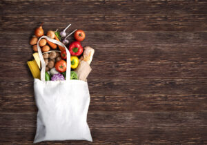 Fabric bag with fresh vegatables on wooden background
