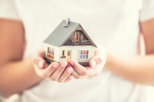 Hands of young woman holding model house