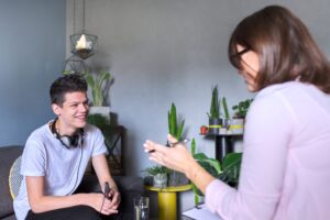 Teen boy talking to psychologist, individual therapy session for teenage with doctor